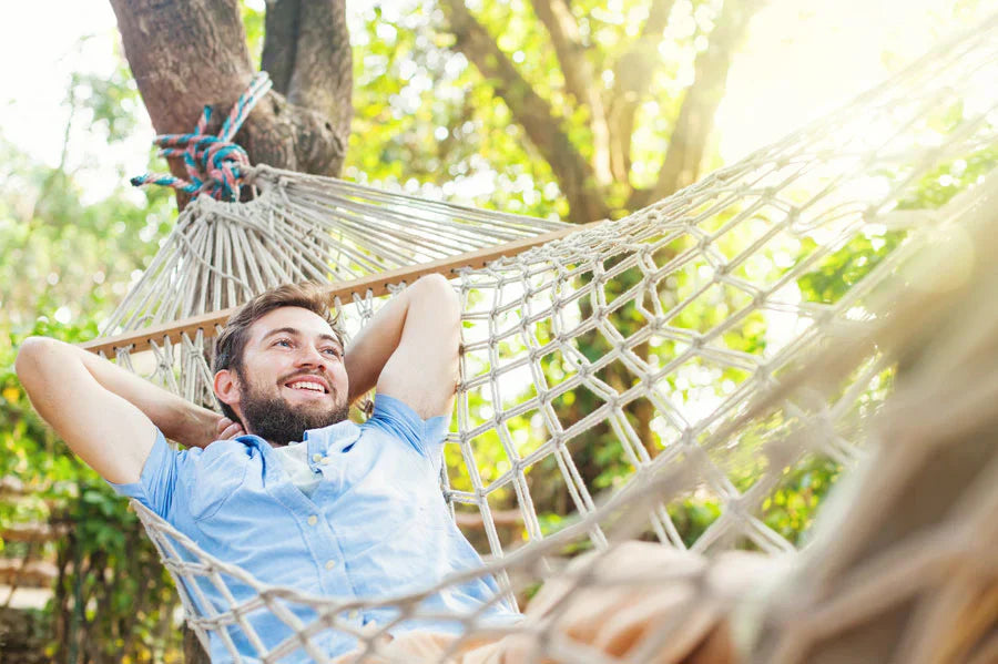 happy man relaxing in a white rope hammock