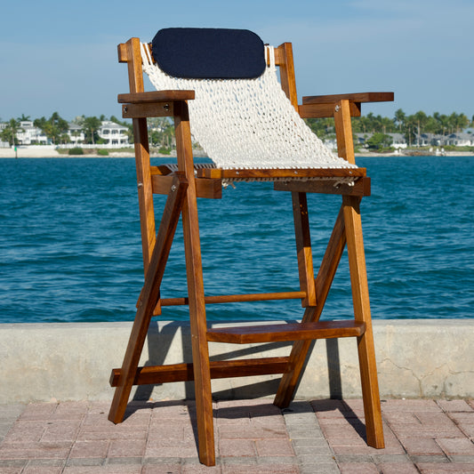 a wood and rope barstool with blue sky and ocean