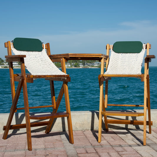 two bar stools overlooking the ocean with rope seats and green pillows