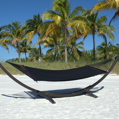 Black Double Caribbean Hammock hanging on the Wood Arc Hammock Stand on a palm-lined beach