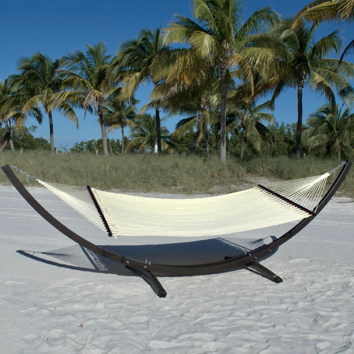 Cream Double Caribbean Hammock hanging on the Wood Arc Hammock Stand on a palm-lined beach