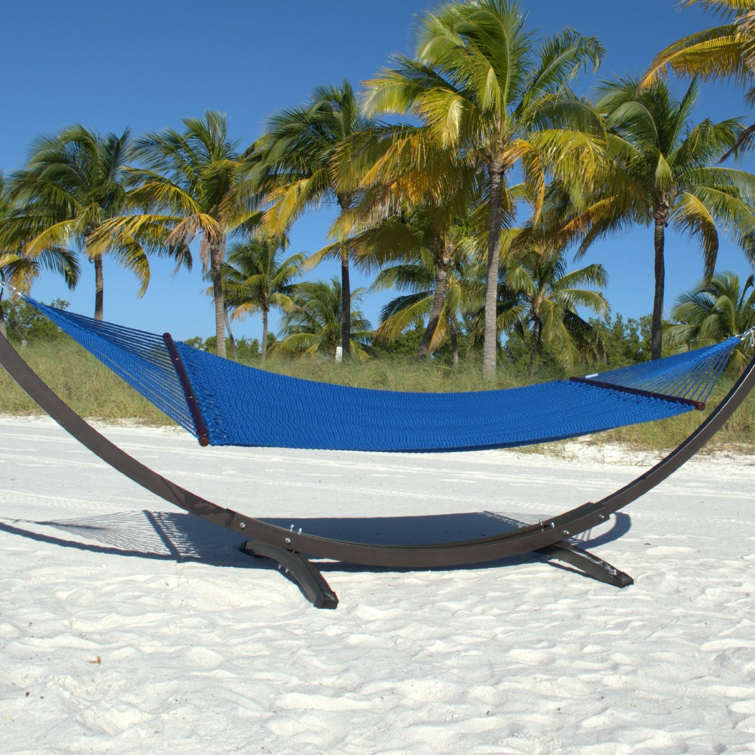 Dark Blue Double Caribbean Hammock hanging on the Wood Arc Hammock Stand on a palm-lined beach