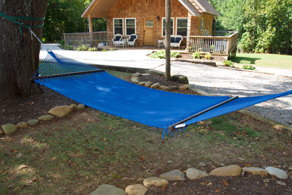 Dark Blue Double Caribbean Hammock hung between trees in front of a cedar-shingled cabin