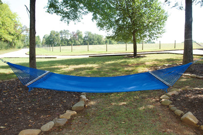 Dark Blue Double Caribbean Hammock hung between two trees in a backyard