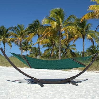 Green Double Caribbean Hammock hanging on the Wood Arc Hammock Stand on a palm-lined beach
