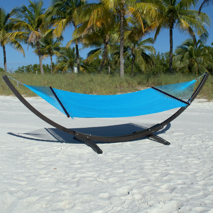 Light Blue Double Caribbean Hammock hanging on the Wood Arc Hammock Stand on a palm-lined beach