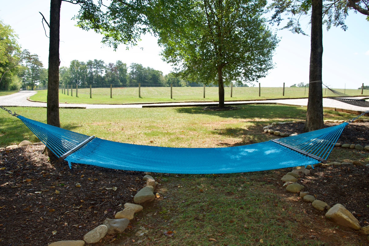 Light Blue Double Caribbean Hammock hung between two trees in a backyard