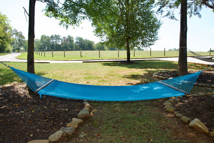 Light Blue Double Caribbean Hammock hung between two trees in a backyard