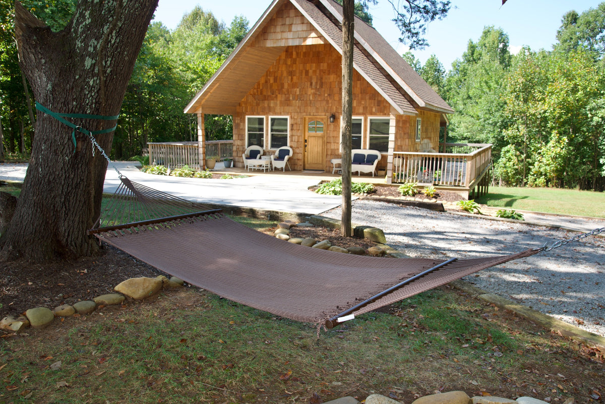 Mocha Double Caribbean Hammock hung between trees in front of a cedar-shingled cabin