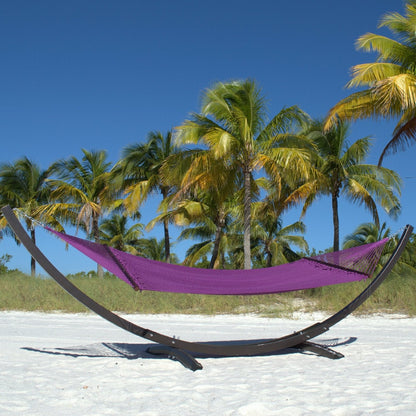 Purple Double Caribbean Hammock hanging on the Wood Arc Hammock Stand on a palm-lined beach