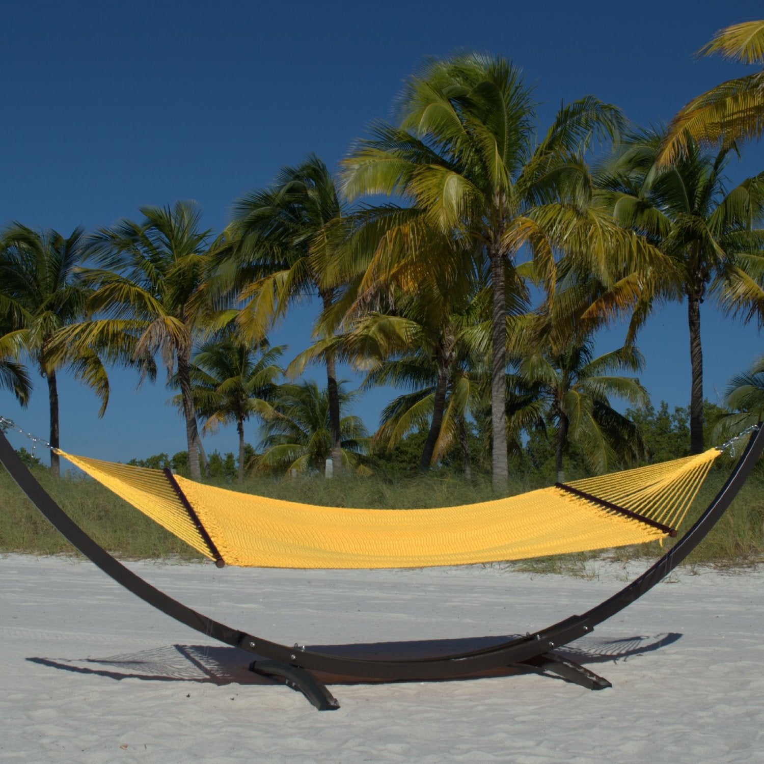 Yellow Double Caribbean Hammock hanging on the Wood Arc Hammock Stand on a palm-lined beach