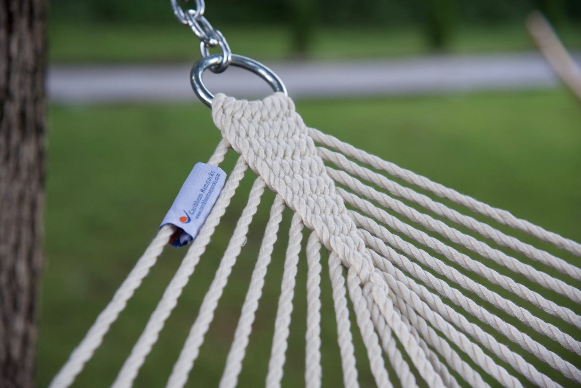 Stainless steel hanging ring, polyester end cords, and clew knot on a cream Island Escape hammock, lawn behind