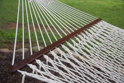 Open-weave polyester bed of a cream Island Escape hammock running to the hardwood spreader bar