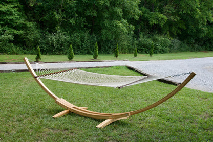 Cream Island Escape hammock hanging on the Wood Arc Hammock Stand on a lawn beside a gravel path