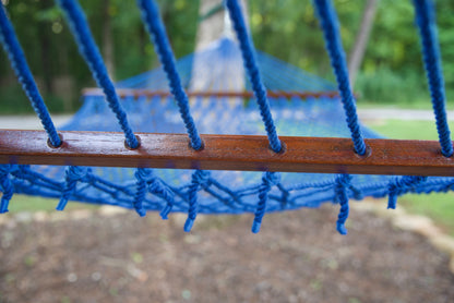 Polyester cords threaded through the drilled hardwood spreader bar of a dark blue Island Escape hammock