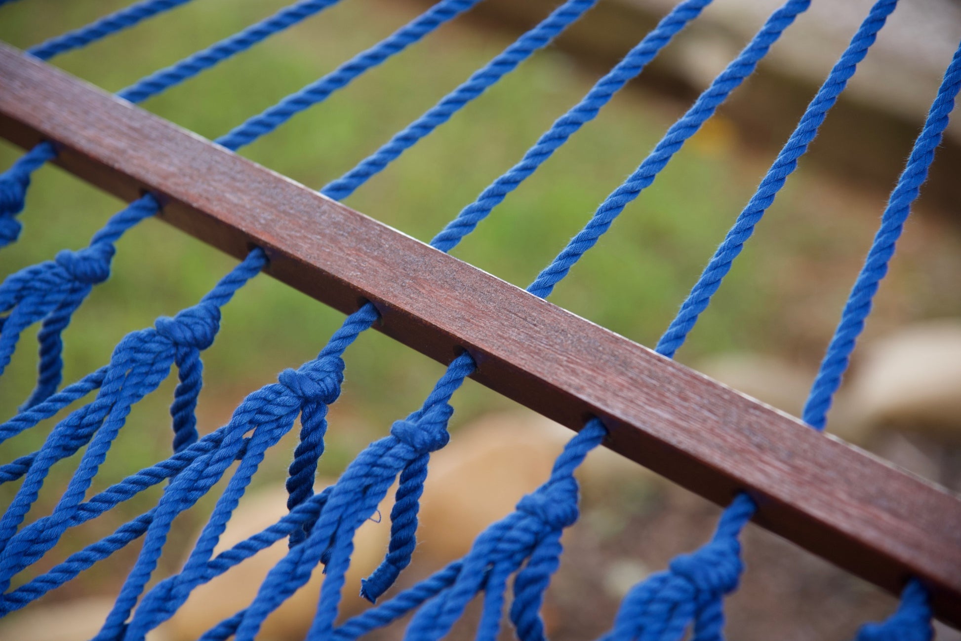 Close-up of the knotted polyester cord ends along the hardwood spreader bar of a dark blue Island Escape hammock