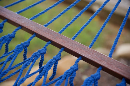 Close-up of the knotted polyester cord ends along the hardwood spreader bar of a dark blue Island Escape hammock