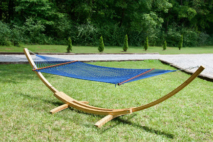Dark blue Island Escape hammock hanging on the Wood Arc Hammock Stand on a lawn beside a gravel path