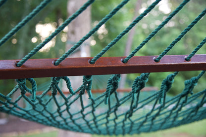 Polyester cords threaded through the drilled hardwood spreader bar of a green Island Escape hammock