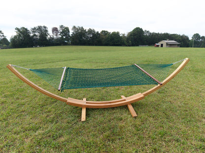 Green Island Escape hammock hanging on the Wood Arc Hammock Stand in a mown field with a barn behind