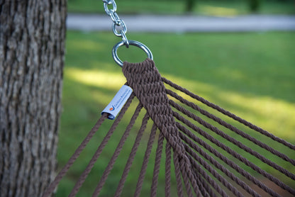 Stainless steel hanging ring, polyester end cords, and clew knot on a mocha Island Escape hammock, tree trunk and lawn behind
