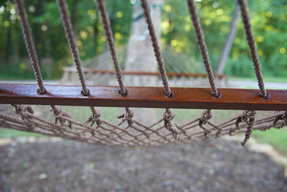 Polyester cords threaded through the drilled hardwood spreader bar of a mocha Island Escape hammock