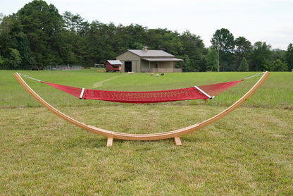 Red Island Escape hammock hanging on the Wood Arc Hammock Stand in a pasture with a barn behind