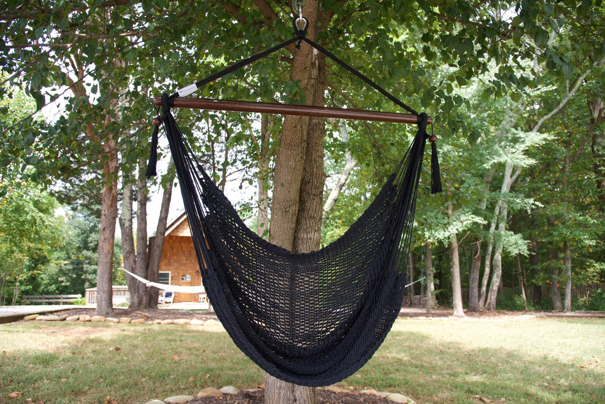Black Island Haven hammock chair hanging from a shade tree in a mown backyard with woods behind