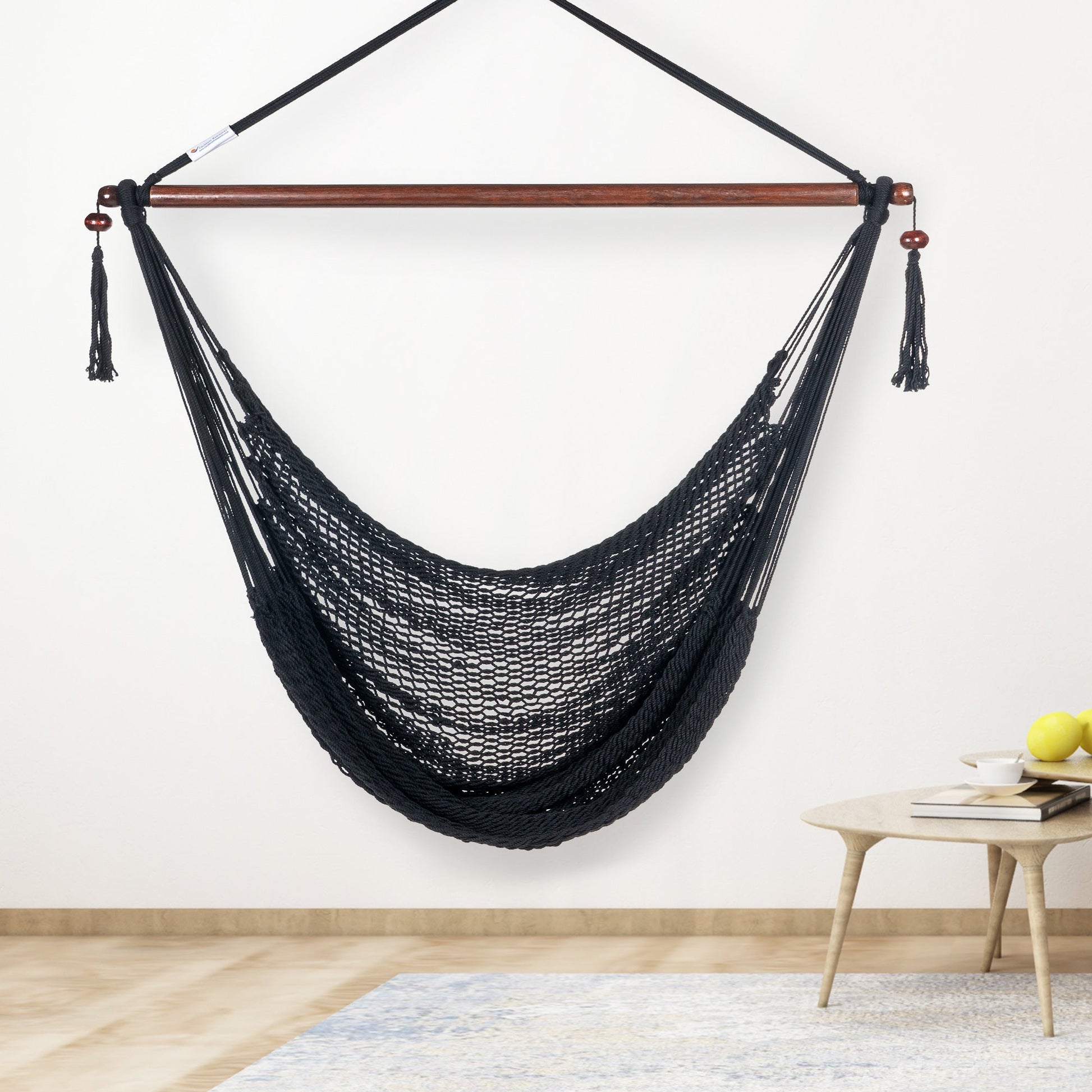 Black Island Haven hammock chair hanging beside a barrel side table and bar stool against a pale grey wall