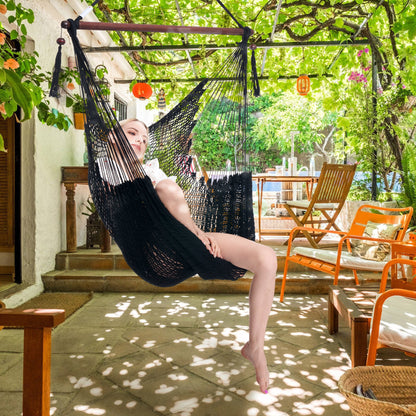 Woman seated in a black Island Haven hammock chair on a shaded patio under a vine-covered pergola