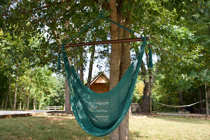 Green Island Haven hammock chair hanging from a shade tree in a mown backyard with woods behind
