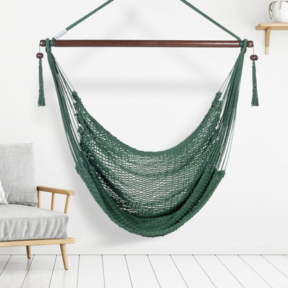 Green Island Haven hammock chair hanging beside a barrel side table and bar stool against a pale grey wall