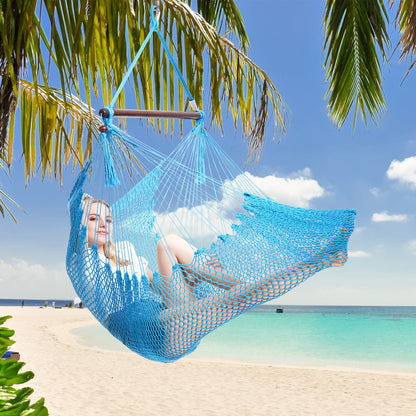 Woman resting in a light blue Island Haven hammock chair hung from a palm tree above a white sand beach