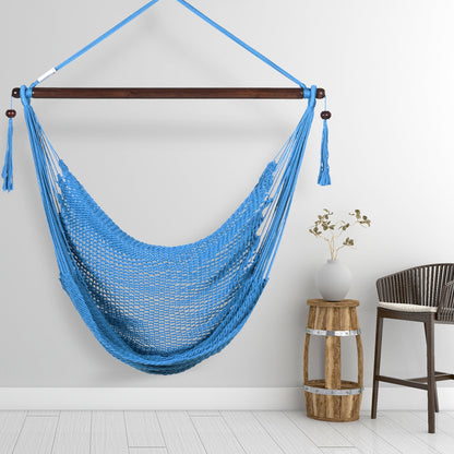 Light blue Island Haven hammock chair hanging beside a barrel side table and bar stool against a pale grey wall