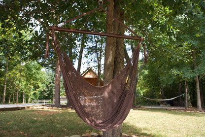 Mocha Island Haven hammock chair hanging from a shade tree in a mown backyard with woods behind
