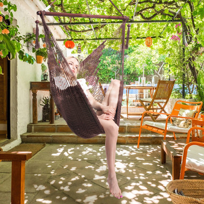 Woman seated in a mocha Island Haven hammock chair on a shaded patio under a vine-covered pergola