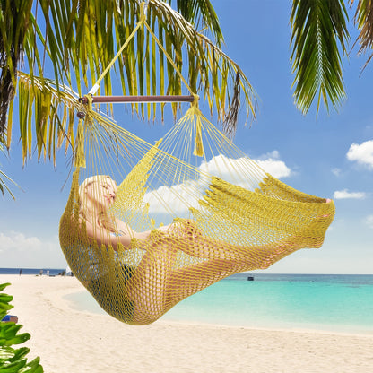 Woman resting in an olive Island Haven hammock chair hung from a palm tree above a white sand beach