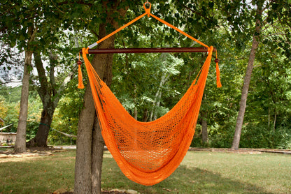 Orange Island Haven hammock chair hanging from a shade tree in a mown backyard with woods behind