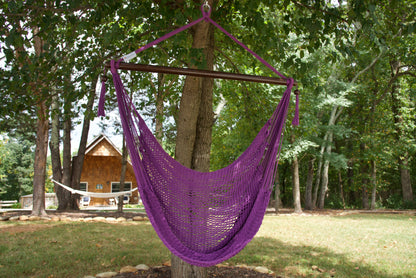 Purple Island Haven hammock chair hanging from a shade tree in a mown backyard with woods behind
