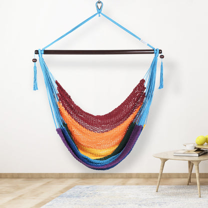 Rainbow-striped Island Haven hammock chair hanging beside a barrel side table and bar stool against a pale grey wall