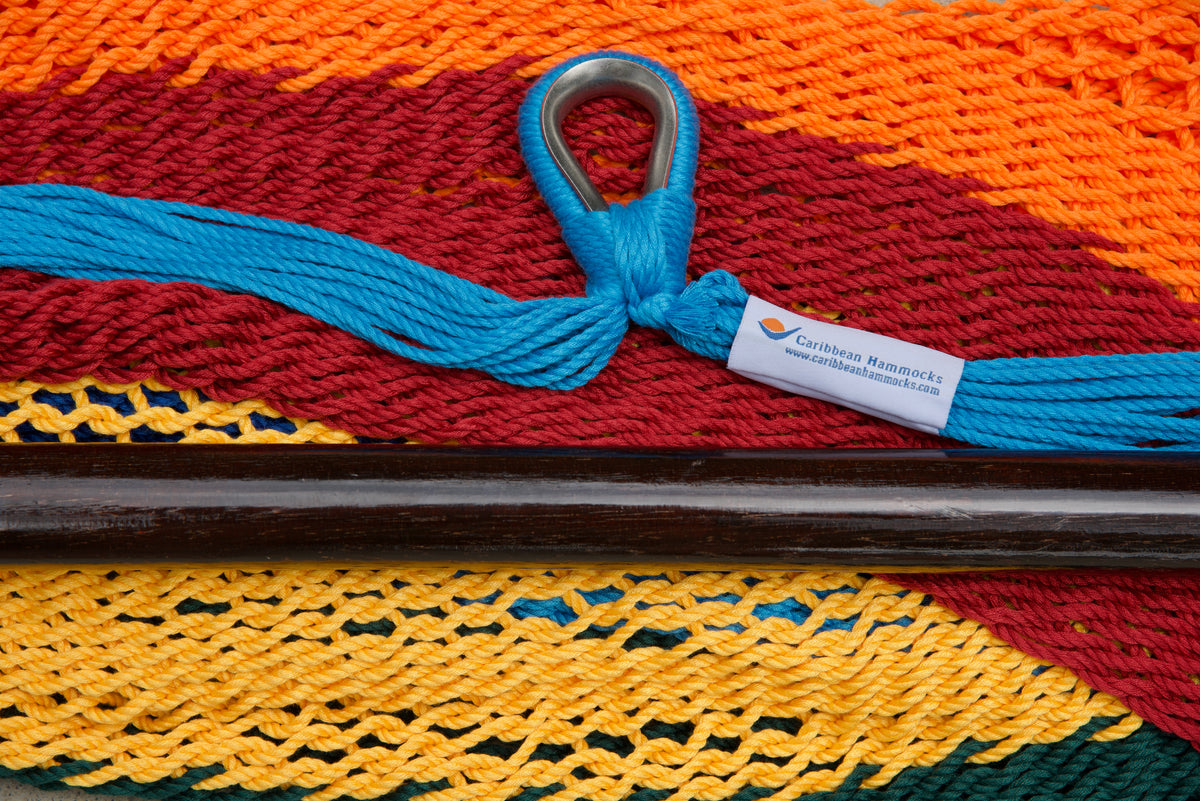 Close-up of the sewn brand label and zinc-plated ring at the seat edge of a rainbow-striped Island Haven hammock chair