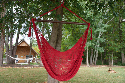 Red Island Haven hammock chair hanging from a shade tree in a mown backyard with woods behind