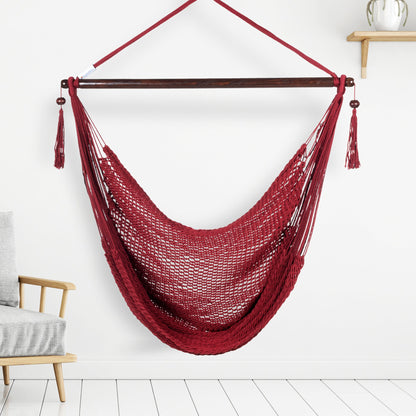 Red Island Haven hammock chair hanging beside a barrel side table and bar stool against a pale grey wall