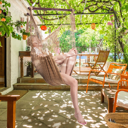 Woman seated in a tan Island Haven hammock chair on a shaded patio under a vine-covered pergola