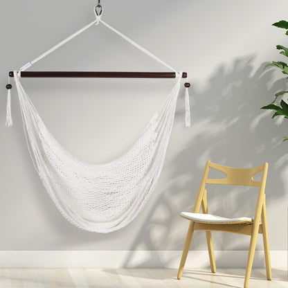 White Island Haven hammock chair hanging beside a light wooden chair against a pale wall