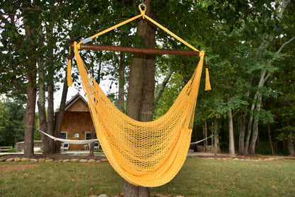 Yellow Island Haven hammock chair hanging from a shade tree in a mown backyard with woods behind