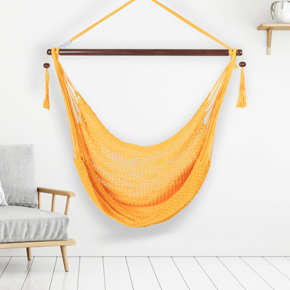 Yellow Island Haven hammock chair hanging beside a barrel side table and bar stool against a pale grey wall