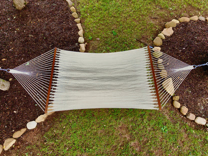 Overhead view of a cream Island Oasis hammock hung between two stone-edged garden beds