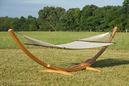 Cream Island Oasis hammock hanging on the Wood Arc Hammock Stand in a grassy field