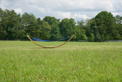 Dark blue Island Oasis hammock on the Wood Arc Hammock Stand seen across a grassy field